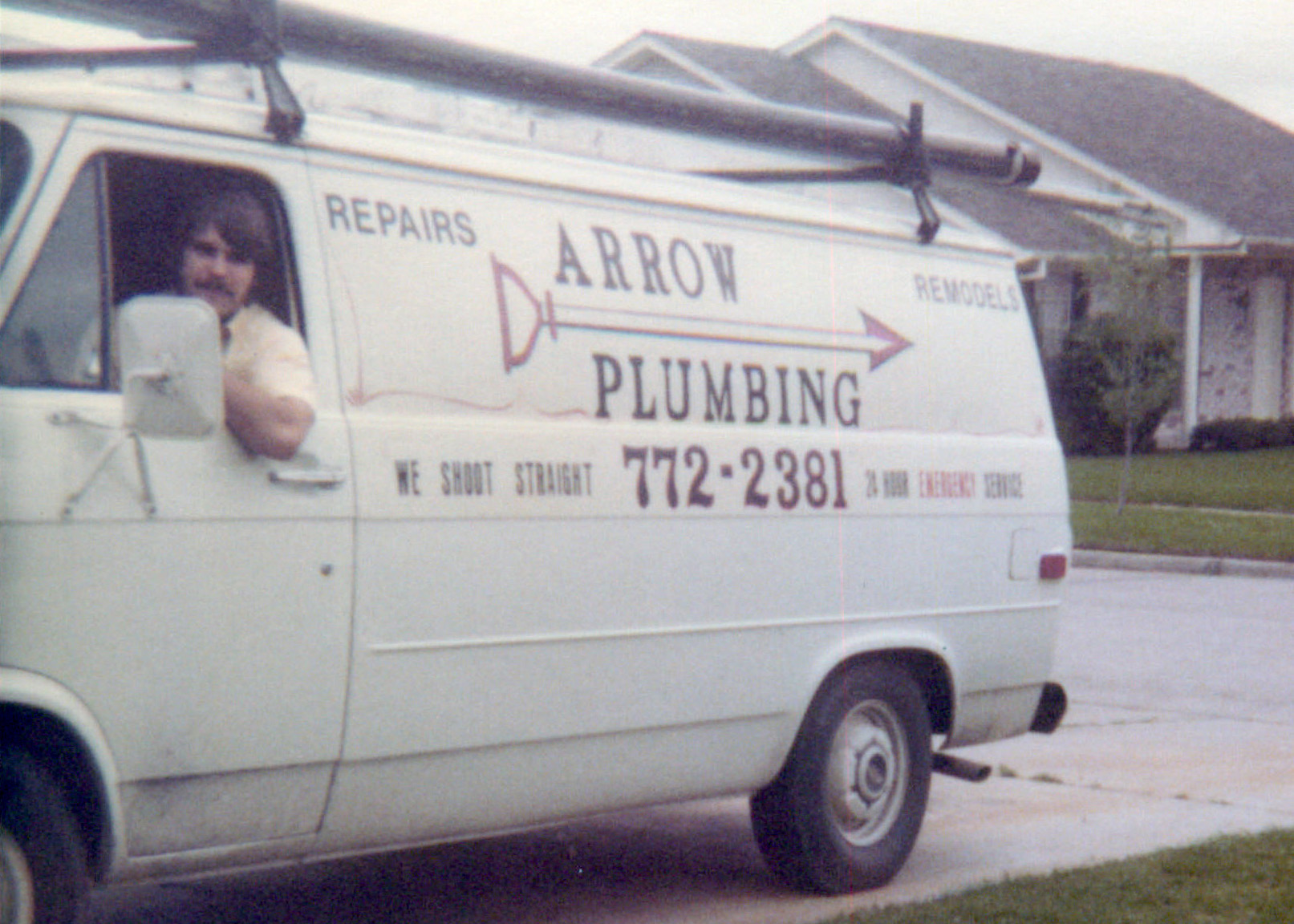 Arrow Plumbing service van with the logo and contact information, featuring a man in the driver's seat, parked in a residential area, symbolizing the company's 48-year legacy of trusted plumbing services in Houston.